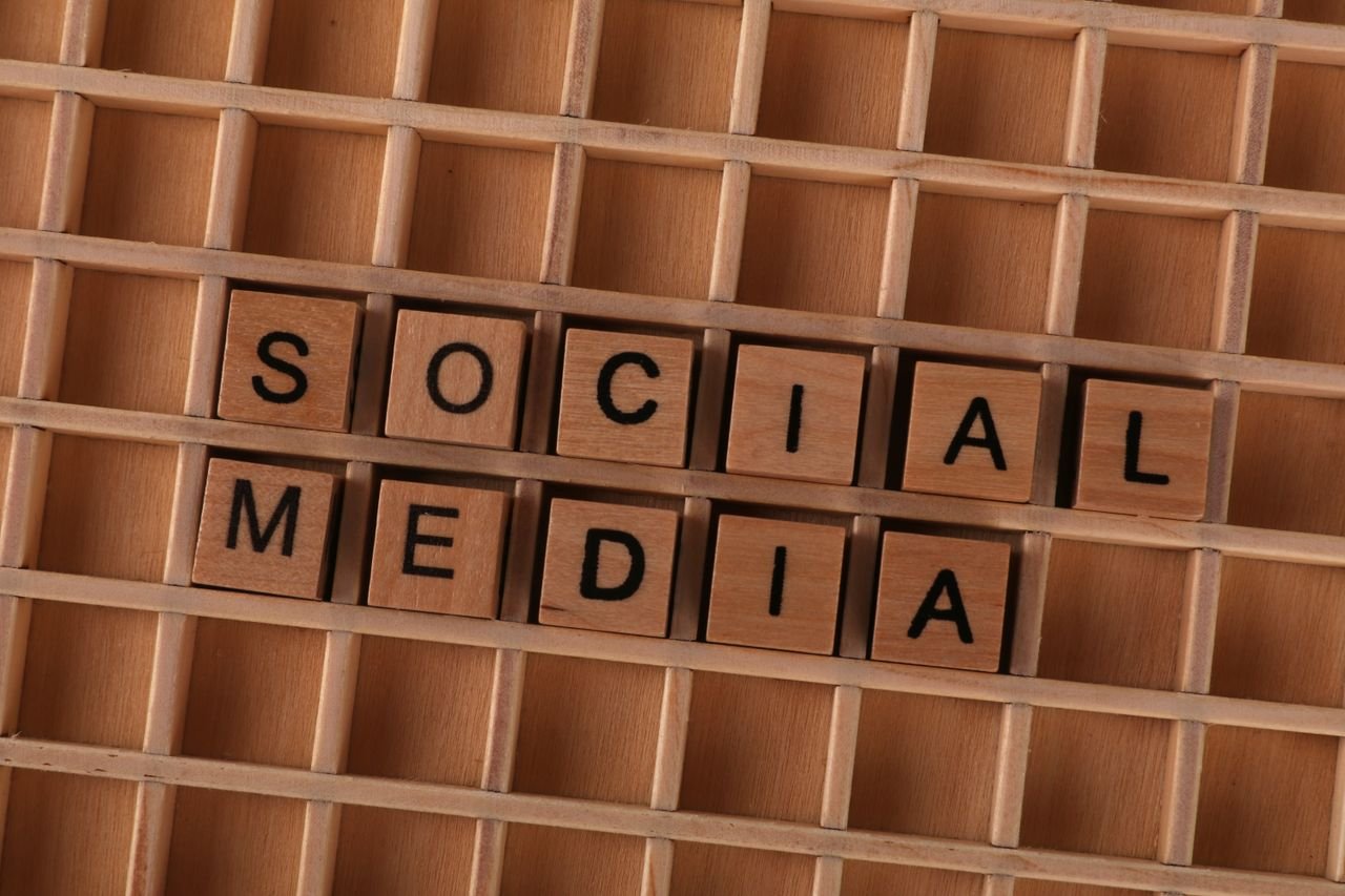 Close-up of wooden letter blocks spelling 'Social Media' on a wooden grid.