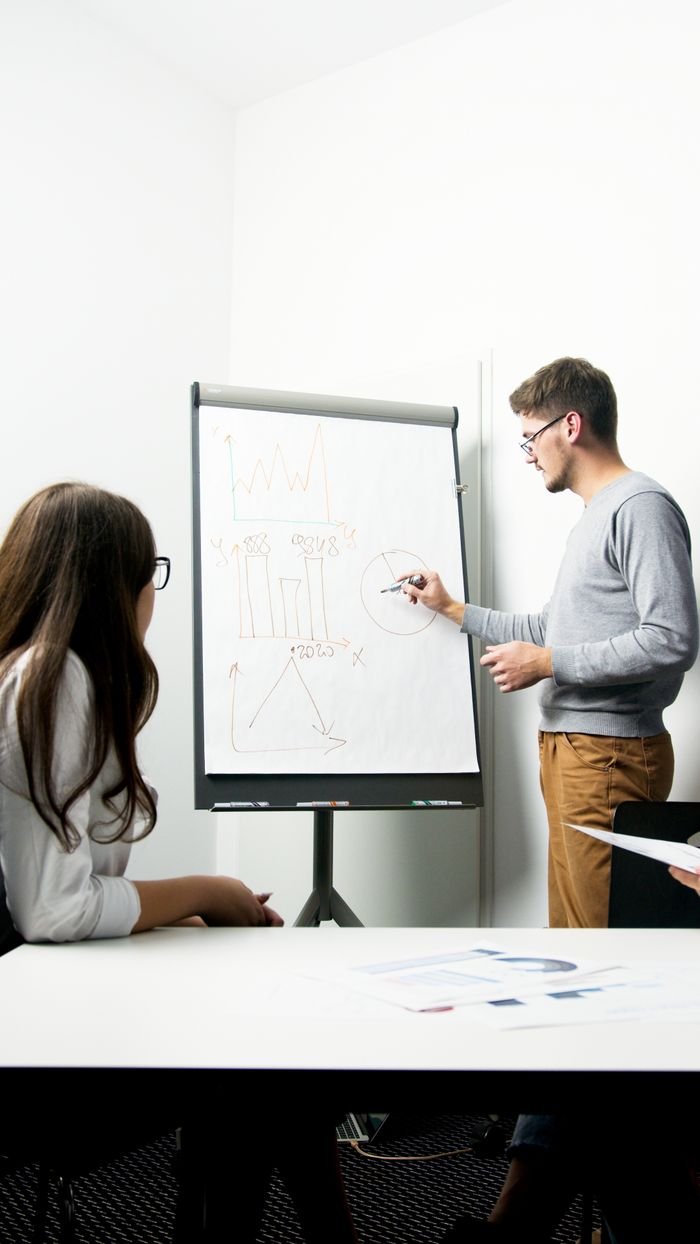 A businessperson giving a presentation with charts in a modern office environment.